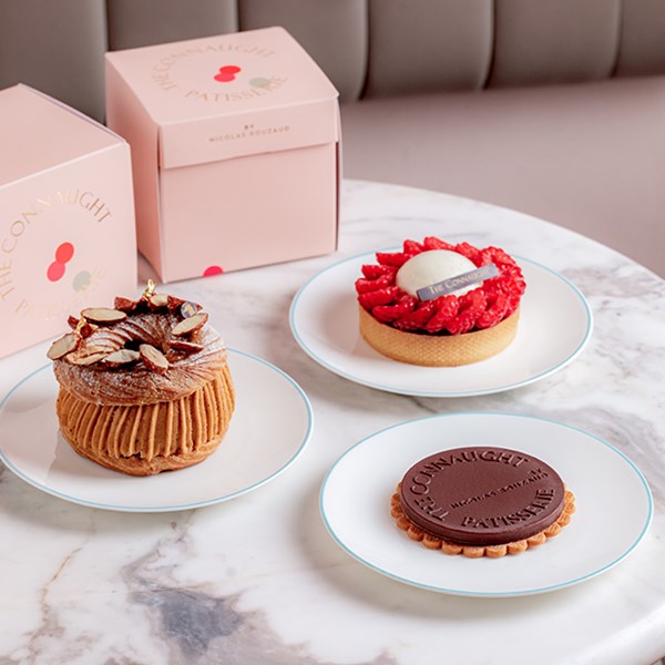 Three cakes on a table, with takeaway boxes next to them.