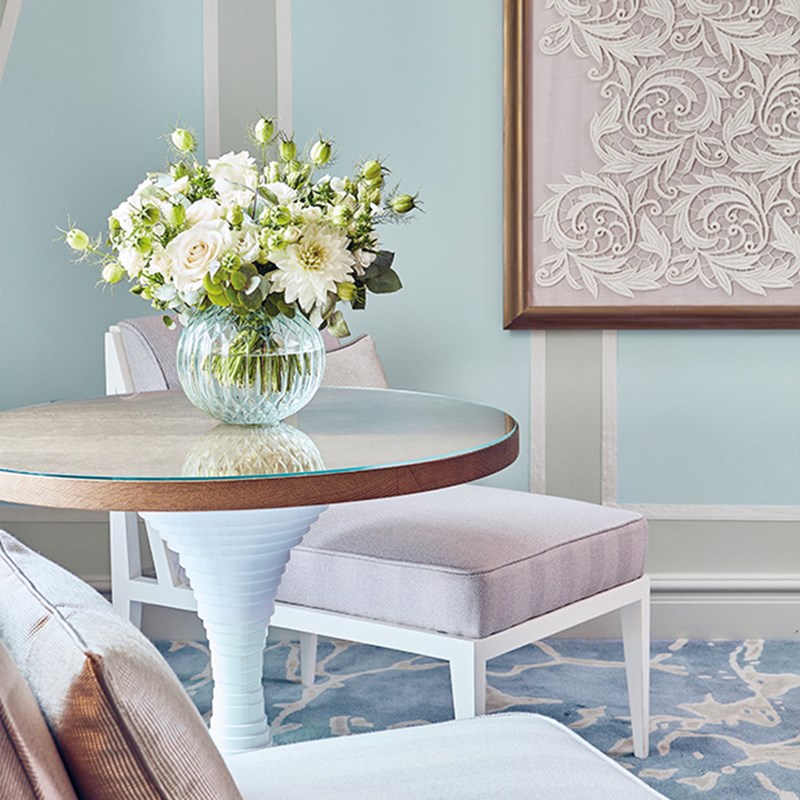A small round table with a vase and flowers on top of it